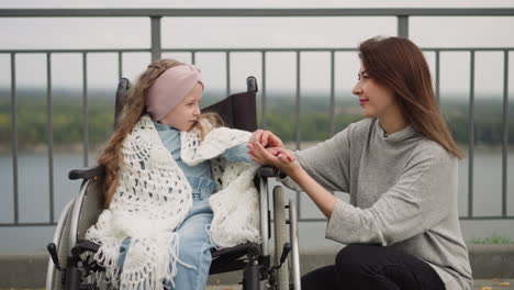 Loving-mom-gently-strokes-hand-of-daughter-with-disability