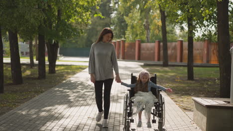 Mutter-Und-Kleine-Tochter-Im-Rollstuhl-Genießen-Den-Spaziergang-Im-Park