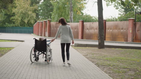 Cheerful-mother-spins-wheelchair-with-little-daughter-around