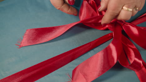 Hands-of-woman-tying-up-bow-from-red-ribbon-on-present-box