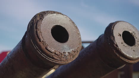 Large-rusty-cannon-muzzles-against-blue-sky-with-white-haze
