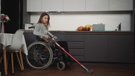 Young-female-with-disability-vacuums-in-kitchen-carefully