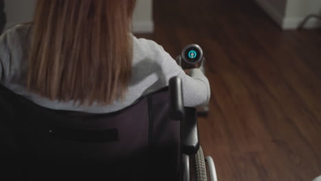 Female-in-wheelchair-collects-dust-using-vacuum-cleaner