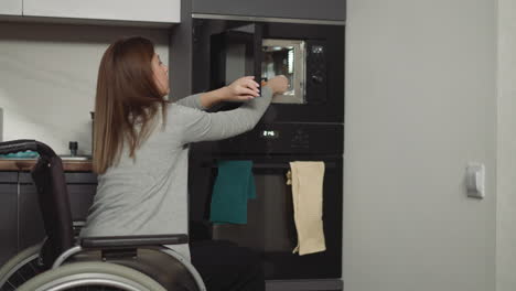 Woman-in-wheelchair-takes-out-plate-with-food-from-microwave