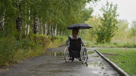 Una-Mujer-Con-Discapacidad-Se-Mueve-Por-El-Camino-Sosteniendo-Un-Paraguas