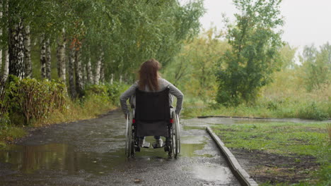 Woman-with-paralysis-moves-in-park-with-puddles-on-windy-day