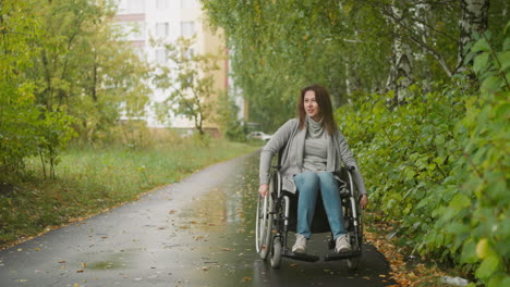Female-person-with-disability-moves-along-path-in-green-park