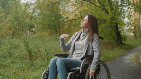 Woman-sits-in-wheelchair-and-looks-into-distance-smiling