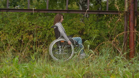 Woman-with-disability-moves-looking-through-shabby-fence