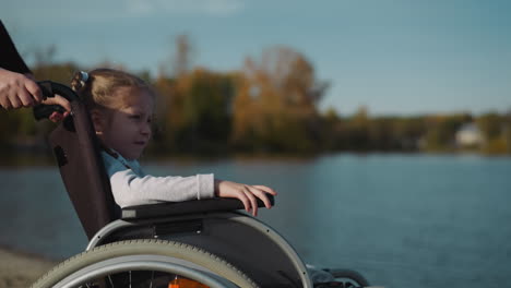 Cute-girl-with-disability-looks-at-flow-of-water-in-river