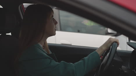 Focused-woman-puts-hand-on-steering-wheel-on-driver-seat