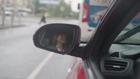 Spiegelbild-Einer-Glücklichen-Frau,-Die-Im-Seitenspiegel-Eines-Roten-Autos-Lächelt