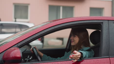 Smiling-woman-drives-car-enjoying-trip-in-rainy-weather