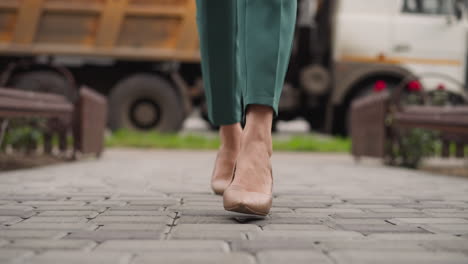 Stylish-woman-in-high-heel-shoes-walks-on-paving-slabs-road