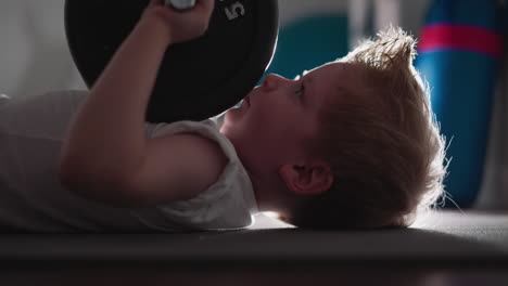 Concentrated-kid-try-to-lift-heavy-barbell-with-little-hands