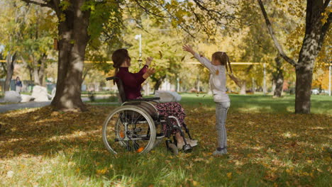 Mother-with-legs-injury-and-daughter-play-with-autumn-leaves