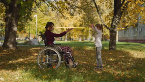 Woman-with-spinal-cord-injury-and-girl-throw-up-dry-leaves