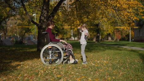 Mother-with-legs-injury-throws-dry-leaves-up-above-daughter