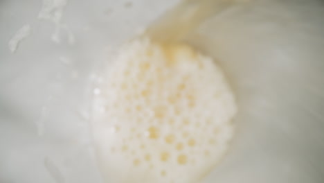 Pouring-fresh-beer-with-froth-into-glass-macro-upper-view