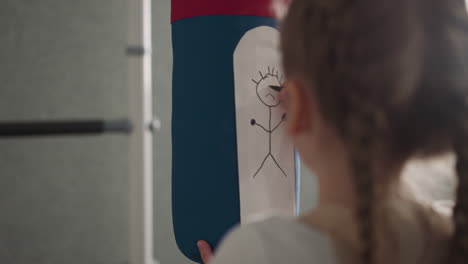 Little-girl-with-plaits-draws-human-figure-on-punching-bag