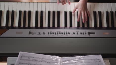 Child-turns-page-of-music-folder-playing-synthesizer