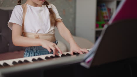 Girl-plays-piano-and-frowns-looking-at-sheet-music-intently