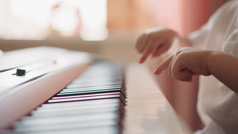 Toddler-boy-plays-piano-with-fingers-on-blurry-background