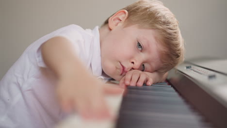 Müder-Junge-Drückt-Hintereinander-Klaviertasten-Und-Legt-Seinen-Kopf-Auf-Die-Tastatur