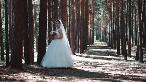 Bride-stands-alone-in-the-woods-and-looks-around