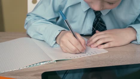 Ext-Cu-Tracking-Schüler-Macht-Hausaufgaben-Schreibt-Einen-Stift-In-Ein-Notizbuch-Auf-Dem-Tisch-Ist-Ein-Tablet