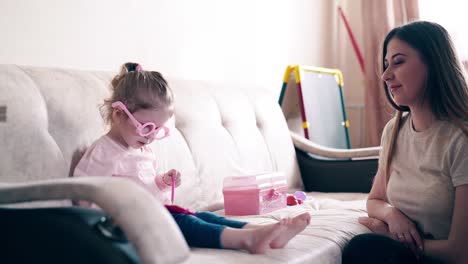 4k-mother-and-sweet-daughter-play-in-the-doctors-daughter-puts-on-toy-glasses-and-writes-diagnosis