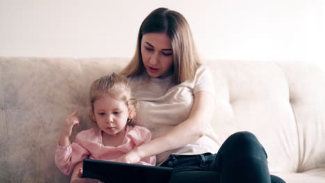 4k-Junge-Süße-Mutter-Und-Kleines-Mädchen-Sitzen-Auf-Der-Couch-Und-Unterrichten-Mit-Einem-Tablet-Computer