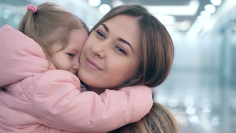 CU-4k-Young-beautiful-mother-hugs-a-little-daughter-they-are-in-a-shopping-center