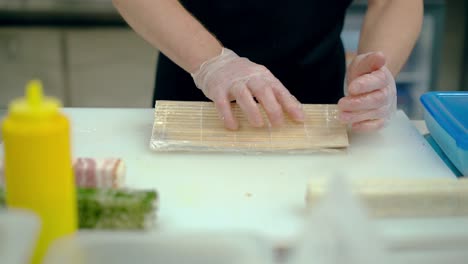 Cook-prepares-a-Japanese-roll-with-rice-and-sesame-seeds