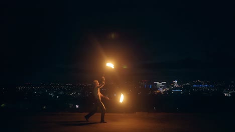 Young-blond-male-dances-with-two-burning-torches
