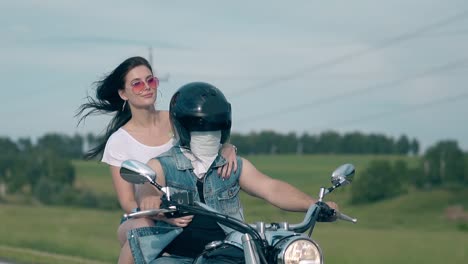 pretty-brunette-girl-holds-man-in-black-helmet-on-motorbike
