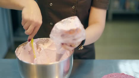 confectioner-in-uniform-puts-pink-cake-cream-in-pastry-bag