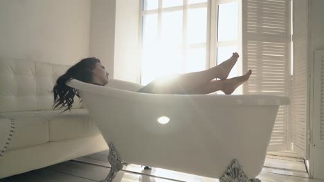Brünette-Frau-Mit-Nackten-Füßen-Posiert-In-Vintage-Badewanne-Am-Fenster