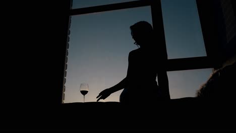 slim-lady-takes-glass-from-windowsill-at-sunset-slow-motion