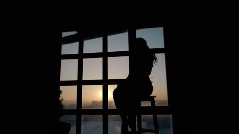 Mädchensilhouette-Richtet-Frisur-In-Der-Nähe-Des-Fensters-Bei-Sonnenuntergang