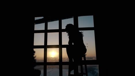 silhouette-of-unhappy-lady-suffering-near-window-at-sunset