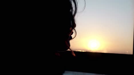Silhouette-Eines-Mädchengesichts,-Das-Bei-Sonnenuntergang-Aus-Dem-Fenster-Schaut