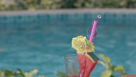 glass-with-straws-and-drink-umbrella-stands-against-pool