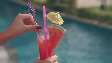 woman-holds-glass-and-puts-pink-and-purple-straws-inside