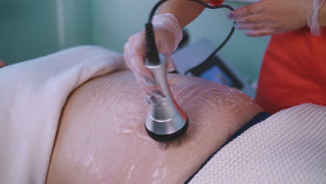 woman-does-vibromassage-to-plump-client-in-clinic-closeup