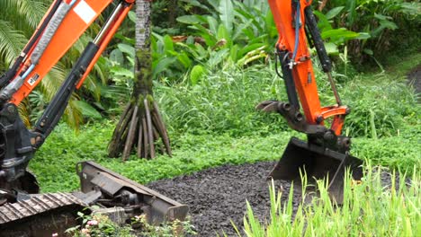 Manual-digger-machine-with-a-bucket-spreading-gravel-on-a-driveway-in-the-tropics