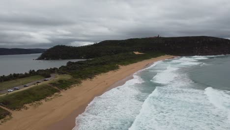 Drone-flying-over-beautiful-sandy-beach-revealing-a-bay-on-the-other-side-of-the-peninsula