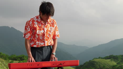 Asian-keyboard-player-at-mountain-in-Vietnam,-handheld-slow-motion