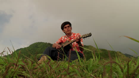 Sitting-guitar-player-at-mountain-in-Vietnam,-closeup-slow-motion
