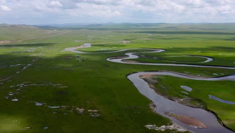Drone-reverse-dolly-above-winding-river-banks-and-oxbow-in-mongolian-grassland-plain